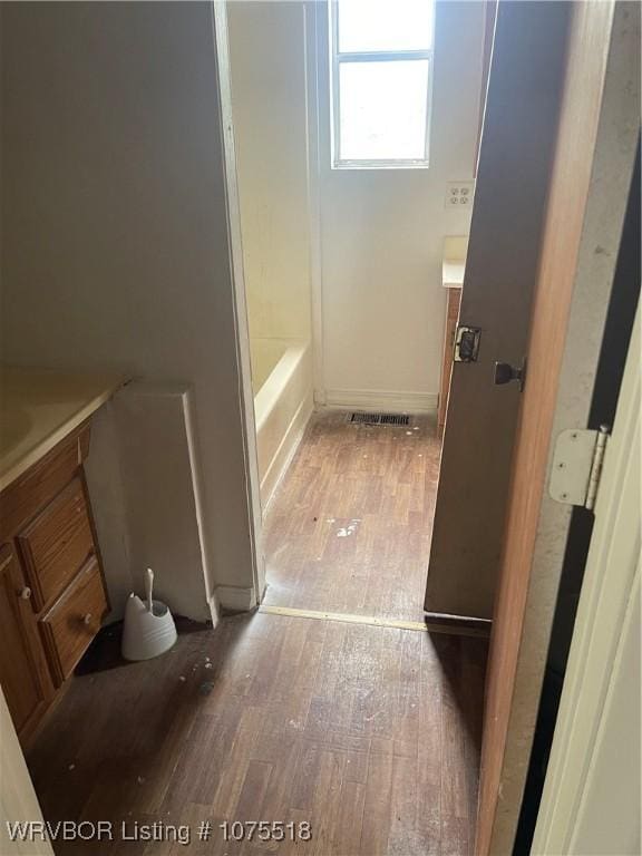 bathroom with a washtub, wood-type flooring, and vanity