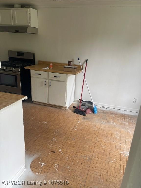 kitchen featuring white cabinets, stainless steel gas range oven, and light parquet flooring