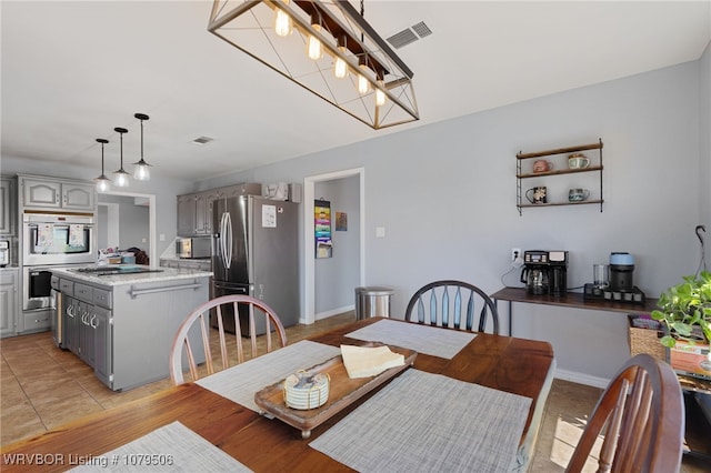 dining area featuring a notable chandelier, visible vents, and baseboards