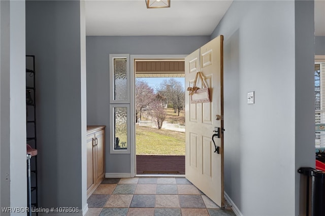 foyer featuring stone finish floor and baseboards