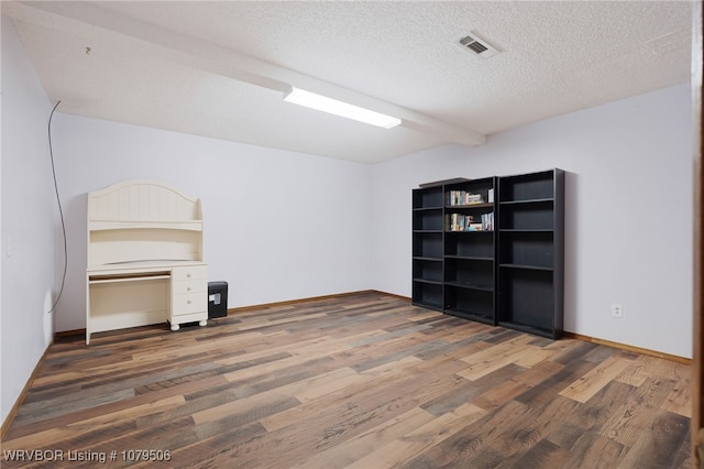 interior space with wood finished floors, visible vents, and a textured ceiling