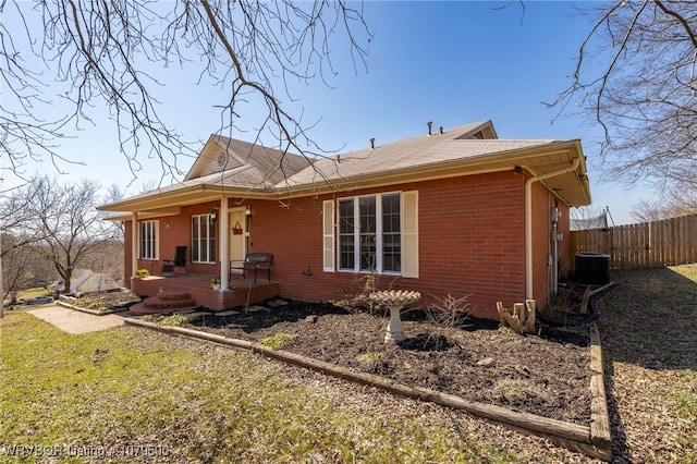 exterior space featuring a yard, fence, brick siding, and central AC