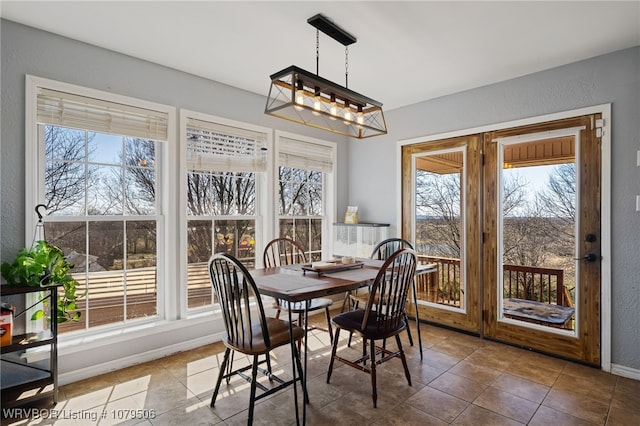 dining space featuring tile patterned flooring, a notable chandelier, a textured wall, and baseboards