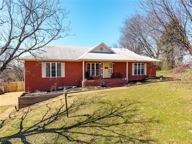 view of front of property featuring brick siding, covered porch, a front yard, and fence