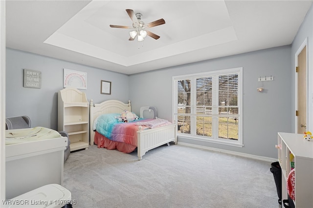 carpeted bedroom with baseboards, a raised ceiling, and ceiling fan