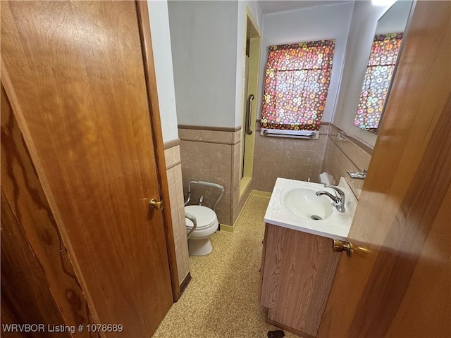 bathroom with vanity, toilet, tile walls, and a shower