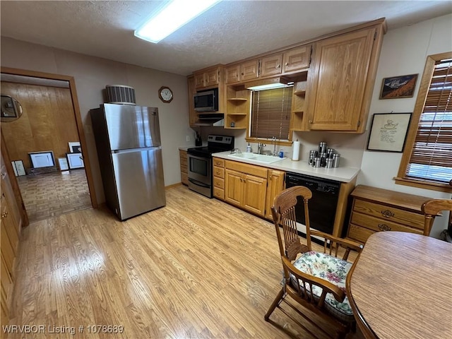 kitchen with stainless steel appliances, sink, a textured ceiling, and light wood-type flooring