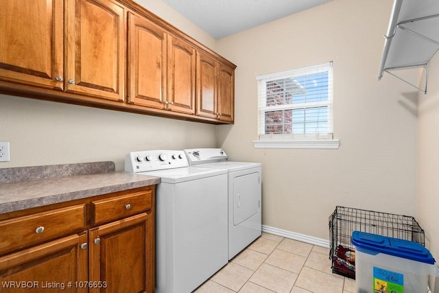 washroom featuring washer and dryer, light tile patterned floors, and cabinets