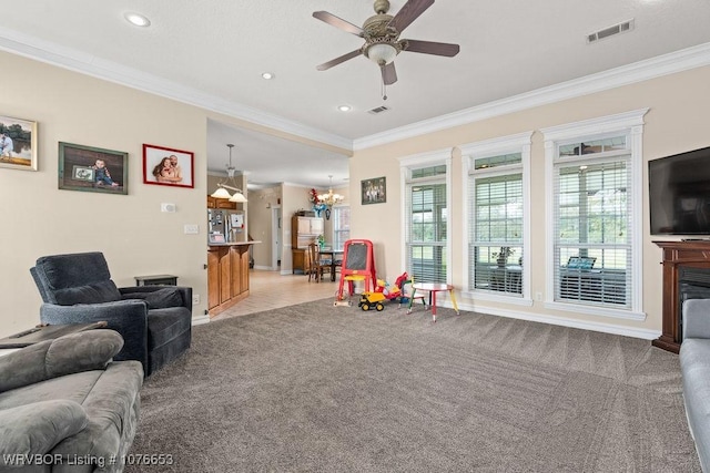 living room with ceiling fan with notable chandelier, light colored carpet, and crown molding