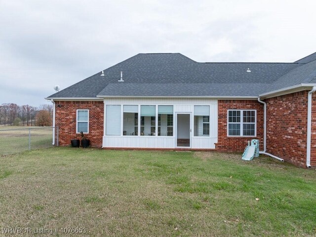 rear view of house featuring a sunroom and a yard