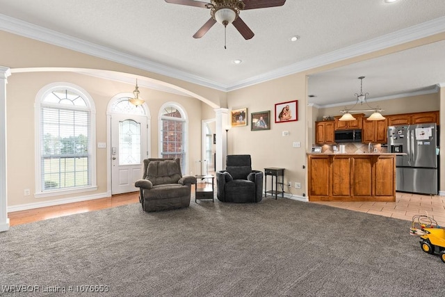 interior space with ceiling fan, light colored carpet, ornamental molding, and ornate columns