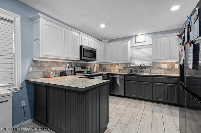 kitchen with sink, tasteful backsplash, appliances with stainless steel finishes, kitchen peninsula, and white cabinets