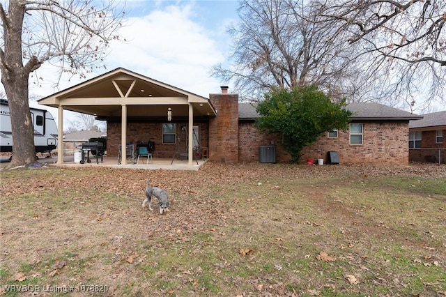 back of property with a lawn, central AC unit, and a patio area