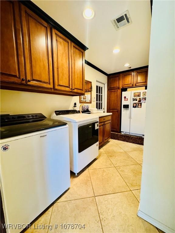 laundry area featuring crown molding, washing machine and clothes dryer, and light tile patterned flooring