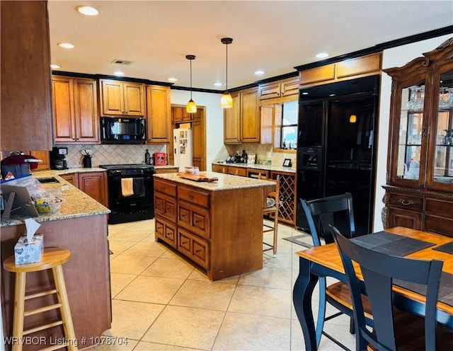 kitchen with a kitchen island, a kitchen breakfast bar, light tile patterned floors, light stone counters, and black appliances