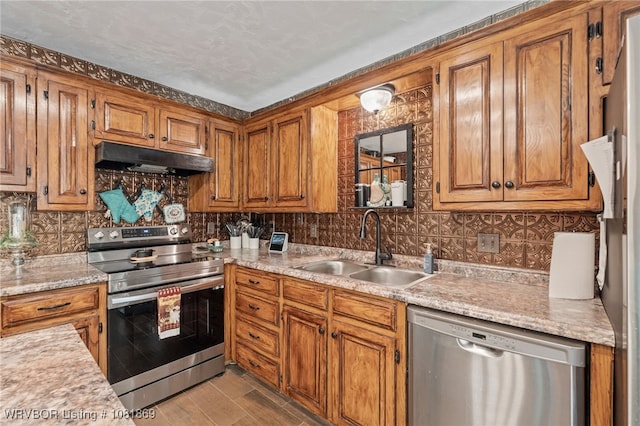 3109 Twin Lakes Pl, Alma, AR 72921 - kitchen featuring appliances with stainless steel finishes, under cabinet range hood, brown cabinets, light countertops, and backsplash