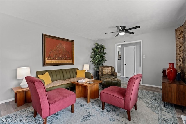 living area featuring a ceiling fan, wood finished floors, and baseboards