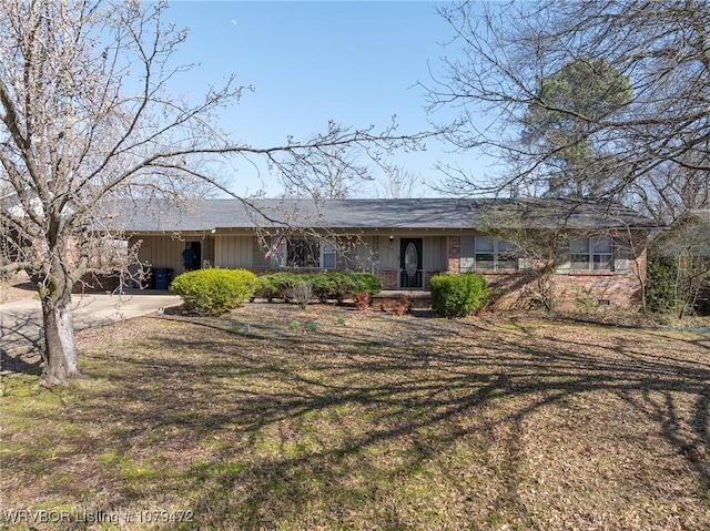 ranch-style house featuring a front lawn, driveway, a porch, board and batten siding, and brick siding