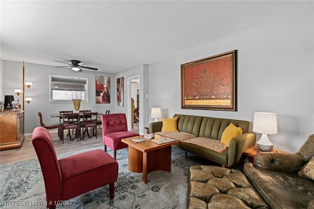 living area with a ceiling fan, baseboards, and light wood finished floors