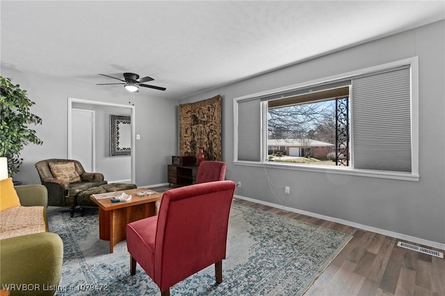 living area with visible vents, baseboards, wood finished floors, and a ceiling fan