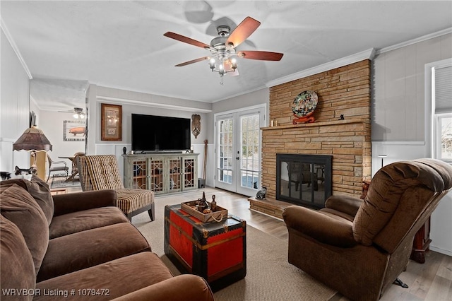 living area featuring a decorative wall, wood finished floors, ceiling fan, and ornamental molding