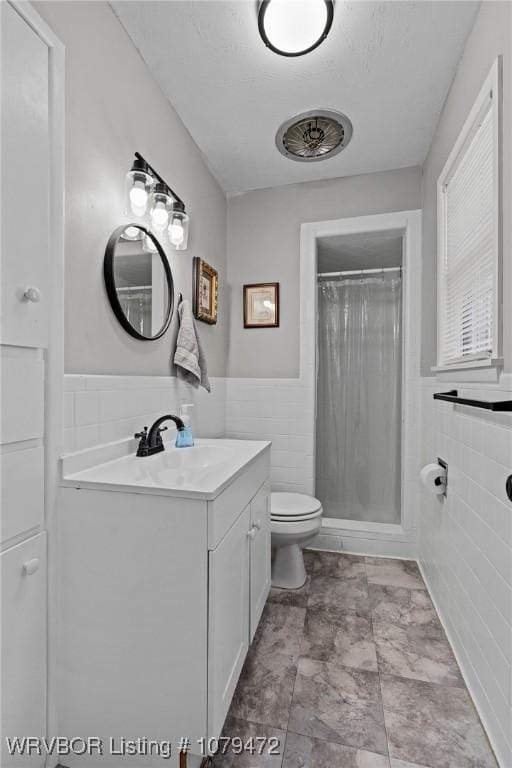 full bath with a wainscoted wall, toilet, tile walls, and vanity