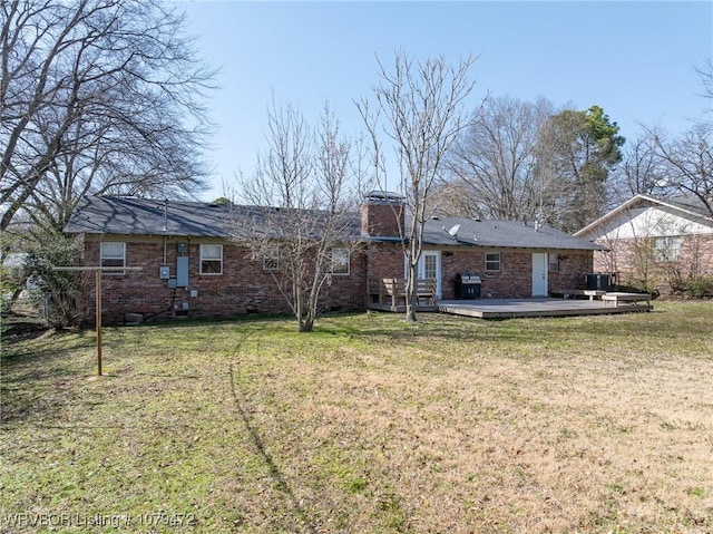 rear view of property with a lawn, a deck, crawl space, brick siding, and a chimney