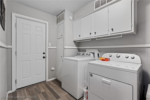 laundry room with wood finished floors, visible vents, cabinet space, wainscoting, and washer and dryer