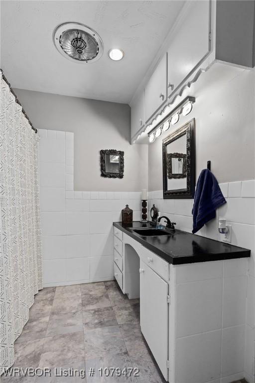 interior space featuring a wainscoted wall, tile walls, and vanity