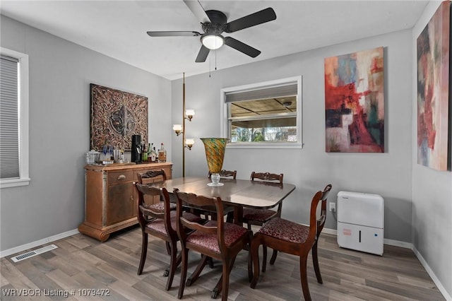 dining space with visible vents, baseboards, ceiling fan, and wood finished floors