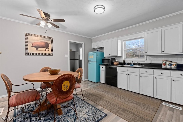 kitchen with visible vents, a sink, ornamental molding, stainless steel appliances, and dark countertops