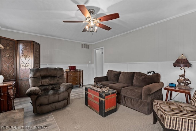 living area with visible vents, wood finished floors, a ceiling fan, and ornamental molding