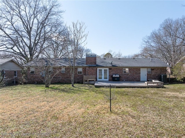 back of property featuring brick siding, central air condition unit, a lawn, french doors, and a chimney