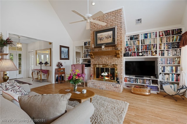 living room featuring high vaulted ceiling, a ceiling fan, wood finished floors, a brick fireplace, and visible vents