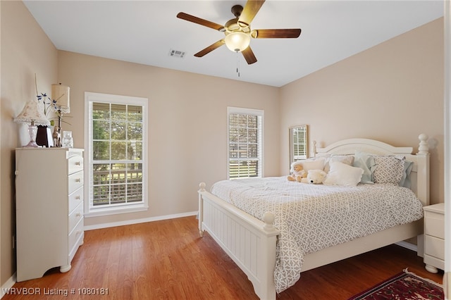 bedroom with visible vents, wood finished floors, baseboards, and a ceiling fan