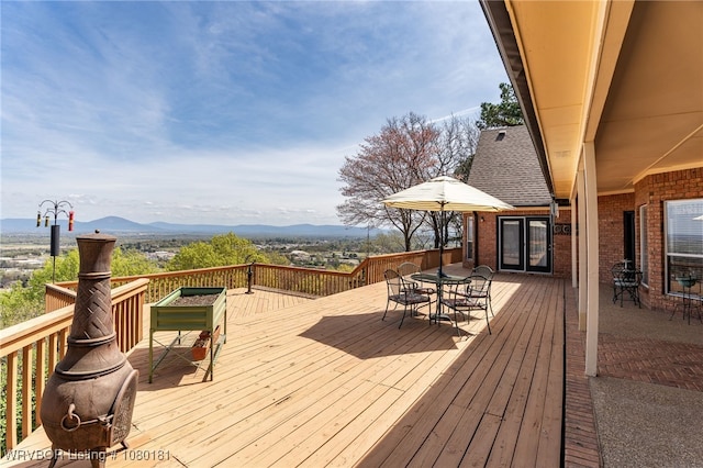 wooden deck with french doors, outdoor dining area, and a mountain view