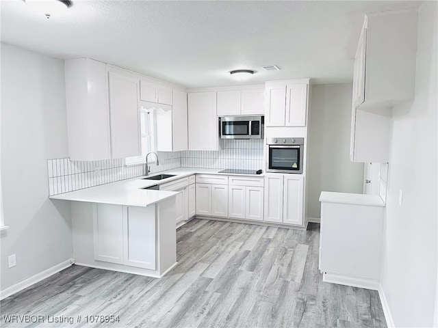 kitchen with white cabinetry, stainless steel appliances, sink, and light wood-type flooring