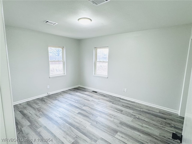 empty room with light hardwood / wood-style floors and a textured ceiling