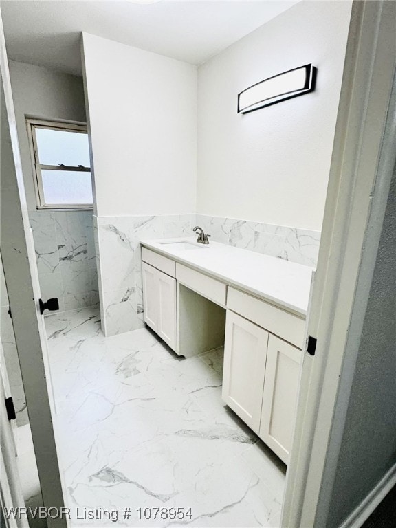 bathroom with a wainscoted wall, marble finish floor, and vanity