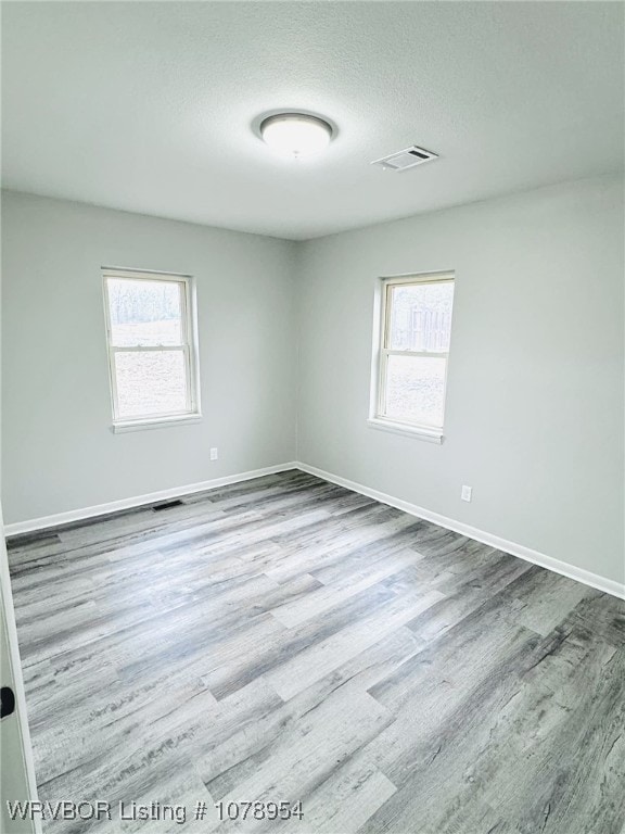 spare room featuring light hardwood / wood-style floors and a textured ceiling