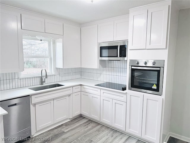 kitchen with backsplash, stainless steel appliances, sink, and white cabinets