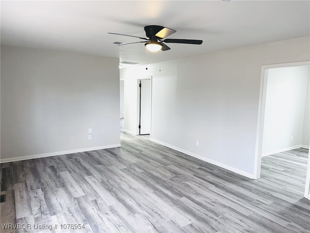empty room featuring visible vents, baseboards, a ceiling fan, and wood finished floors