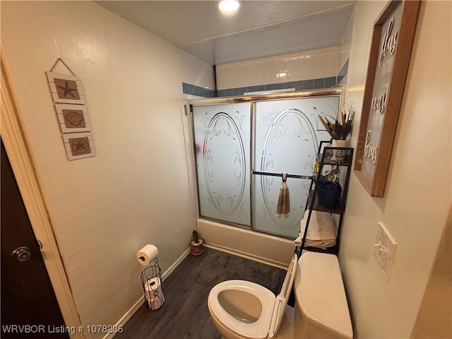 bathroom featuring wood-type flooring, toilet, and bath / shower combo with glass door