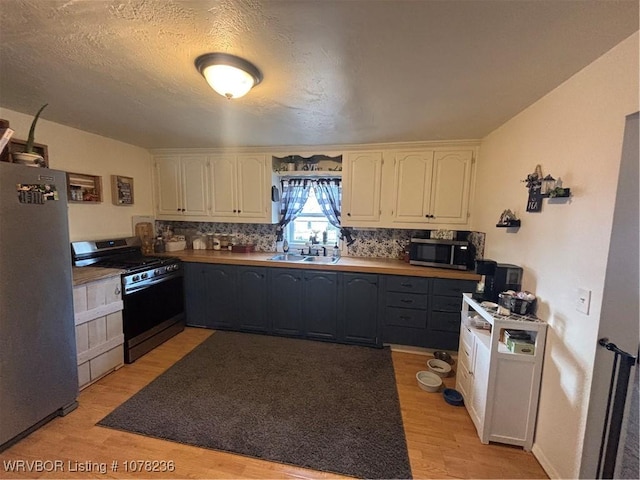 kitchen featuring decorative backsplash, light hardwood / wood-style flooring, white cabinets, and stainless steel appliances