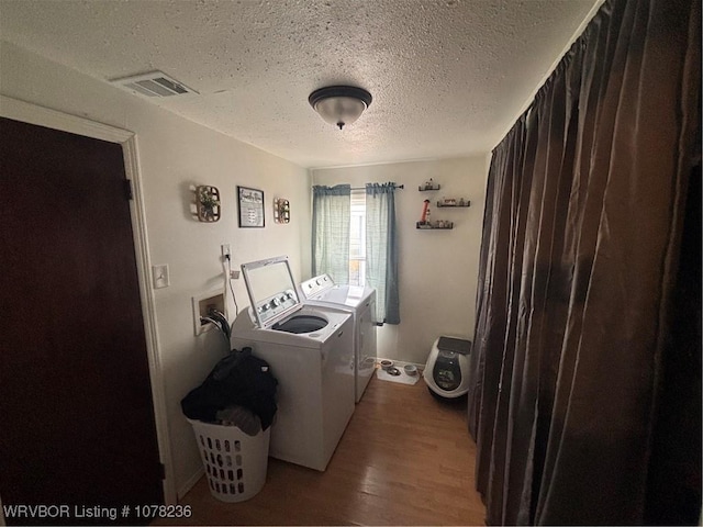 washroom featuring hardwood / wood-style floors, a textured ceiling, and washing machine and clothes dryer