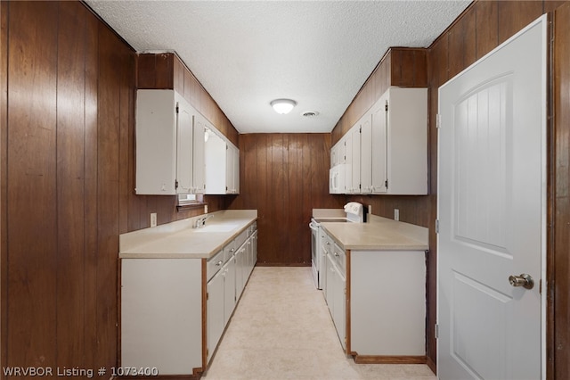 kitchen featuring wood walls, white appliances, sink, and white cabinetry