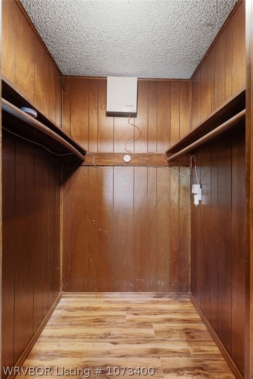 walk in closet with light hardwood / wood-style floors