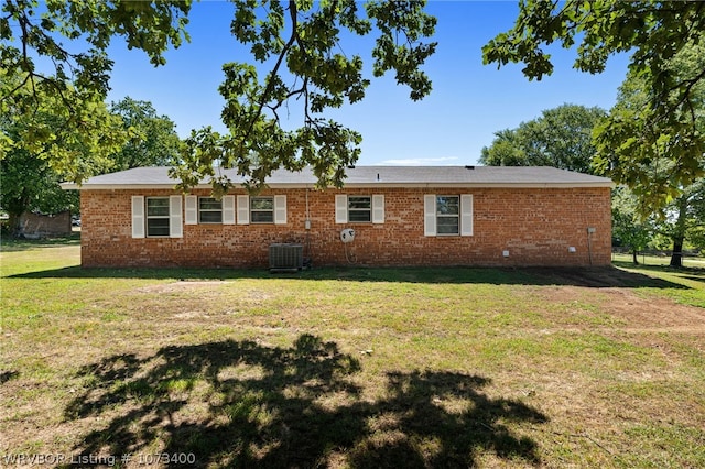 rear view of property featuring central AC unit and a yard