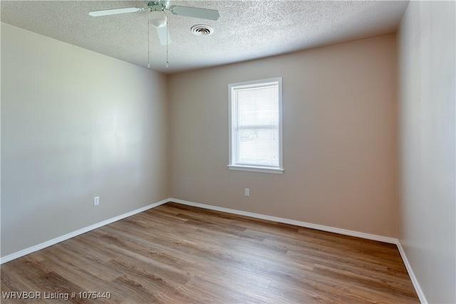 empty room with ceiling fan, light hardwood / wood-style floors, and a textured ceiling