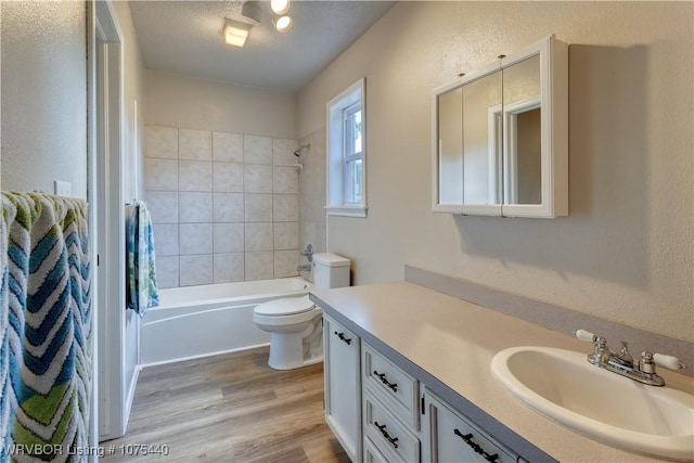 full bathroom featuring vanity, hardwood / wood-style flooring, toilet, a textured ceiling, and shower / tub combo with curtain